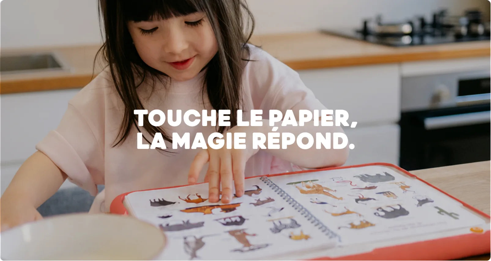 Une enfant pose ses doigts sur un livre HopiPlay : touche le papier, la magie répond.
